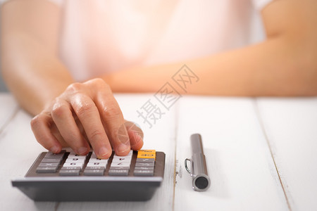成本使用桌上计算器的女商人选择焦点在光线上钱账单图片