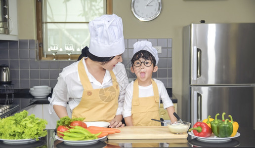 美食成人亚洲年轻母亲有儿子和的亚洲女年轻母亲烹饪沙拉食物配菜端着番茄和胡萝卜盘子里放铃椒供幸福家庭煮饭时用在家做享受生活方式健康图片