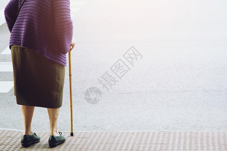 身持徒步棍的老年妇女站在步行道人上等待独自穿过街道的概念在对面高到斑马十字路口阴影职员人行横道图片