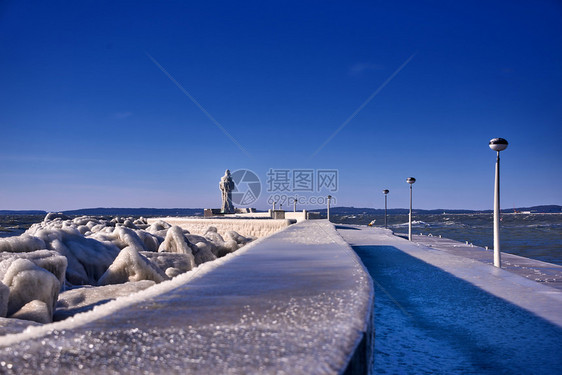 暴风雨寒冷的灯塔和码头在暴风寒冬日岩石天图片