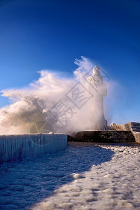 寒冷的灯塔和码头在暴风寒冬日飓涂层水图片