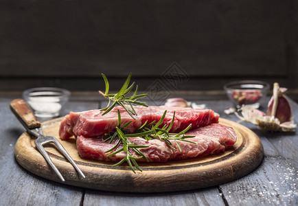 肋眼木板上配有迷迭香大蒜盐和胡椒的生肉绿色有机图片