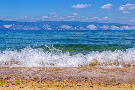 石头海岸线在Baikal湖海岸和Olkhon岛背景海滩山区湖中纯绿水和有云的蓝天俄罗斯在西伯利亚夏日发生波浪相照的风景图象Bai图片