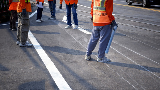 地点天公路工人小组的低正致力于在沥青公路上为油画交通彩色线打标识有选择地重点关注该城市街道表面的铁轨交叉点安全图片