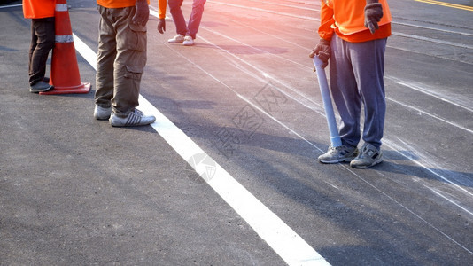 运动鞋在职的公路工人小组低正致力于在沥青公路上为油画交通彩色线打标识有选择地重点关注该城市街道表面的铁轨交叉点维护图片