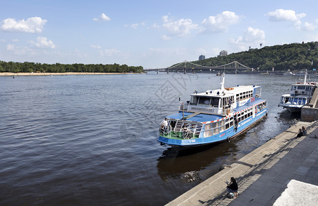 旅游水艇停靠在基辅Dnieper河的码头其背景是横跨河流和城市林木公园斜坡的桥梁游船停靠在Dnieper河的城市码头欢乐船停靠在图片