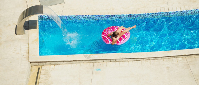 快乐的小孩在海边热带度假胜地的一个热带度假村玩蓝水游泳池暑假概念可爱女孩游泳池水孩子设备充气游泳圈健康脸假期图片