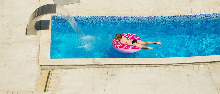 圆圈旅行滴快乐的小孩在海边热带度假胜地的一个热带度假村玩蓝水游泳池暑假概念可爱女孩游泳池水孩子设备充气游泳圈图片