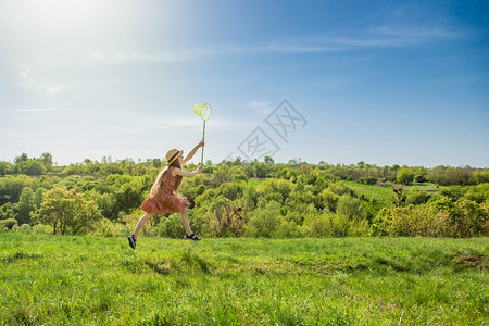 随意的畅快女孩在夏日阳光微笑的女孩在蓝天上拿着蝴蝶网云彩女孩在