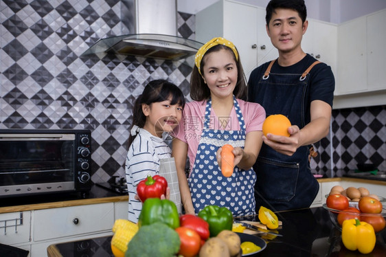 吃亚洲家庭正在做饭父母女儿家里厨房做饭节假日的家庭活动和娱乐快概念是家庭活动在娱乐中欢的理念微笑美丽图片