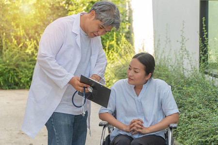医生拿着病历给坐在轮椅上的病人讲解病情图片