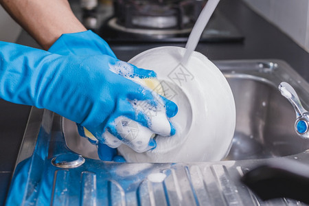 人类一个穿着蓝色橡胶手套的近身男子在厨房水槽里用洗碗液杯子他当时正戴着一个蓝色橡胶手套家务干净的图片