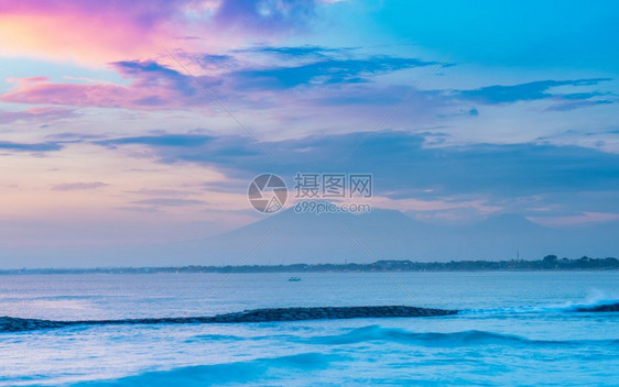 冲浪晴天放松将太阳与远处看到的火山同在库塔Kuta图片