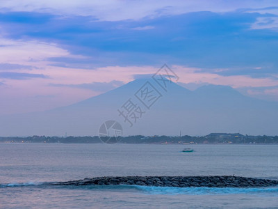 旅游海滩将太阳与远处看到的火山同在库塔Kuta夏天图片