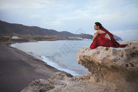 卵石年轻黑发女舞睡在海滩附近的石头里自然阳光图片