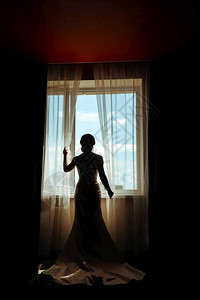 忧虑窗帘面纱新娘在边穿着裙子向窗外看时装新娘在窗边穿着衣服向窗外看图片