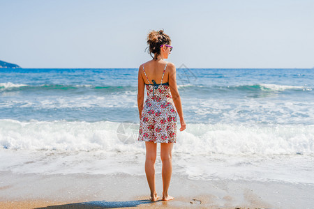 身着夏服站在海边或滨滩的年轻女青背后视线度假旅行期前往海边看风景夏天独自的女图片