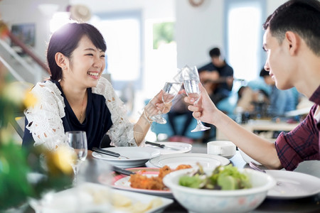 女孩亚裔年轻夫妇一起坐在厨房的餐桌边享受浪漫晚餐饮时的浪漫宴夜饮友谊微笑图片