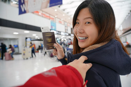 女士随意的候机时手抚亚洲肩在机场迎接朋友手拿大行李护照旅客和友好的概念脸图片