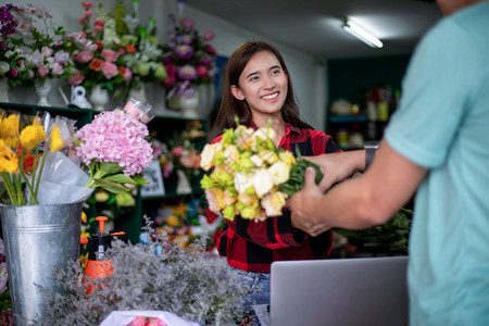 为了一家小型花店的亚洲女老板她拿着鲜花送货给商店的顾客成熟一种图片