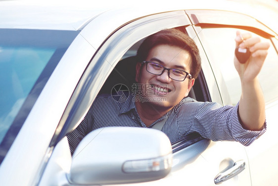 男人新的倾斜快乐男司机展示车钥匙靠在门上图片