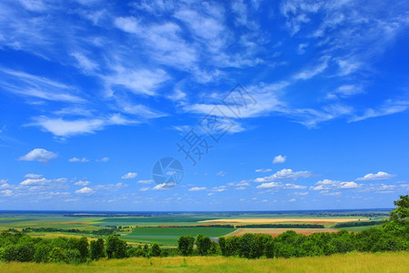 超过沉降风景优美在丽的农村景观上画出夏月的云彩景色草坪和林地田野草原森林道路村庄和远方背景阳光温暖的天气住区上树木图片