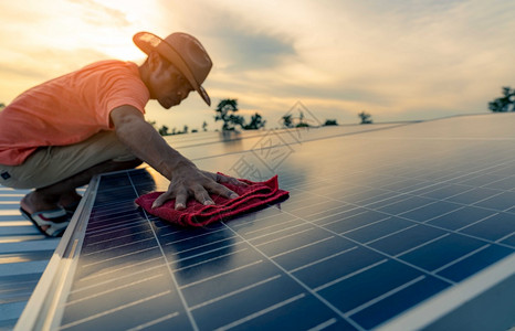 太阳的光在屋顶太能电池板或光伏模块维护上用清洁太阳能板的人清洁太阳能板可持续源和再生用于绿色概念未来能源利用太阳技术的应用为绿色图片
