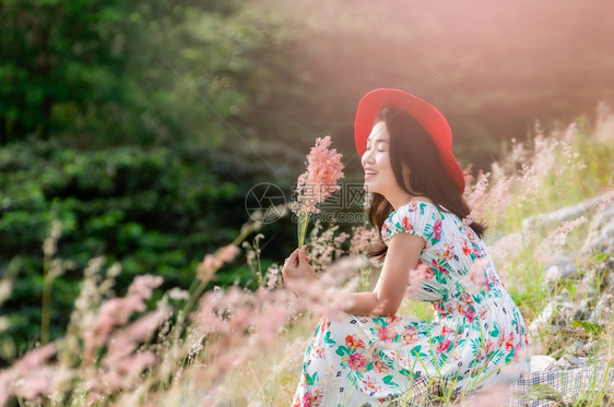 年轻的丰富多彩身穿天然花朵裙子和红帽的美丽女坐在粉红色草地上位于泰国兰邦美昌梅水上鲜花中的美丽妇女场地图片