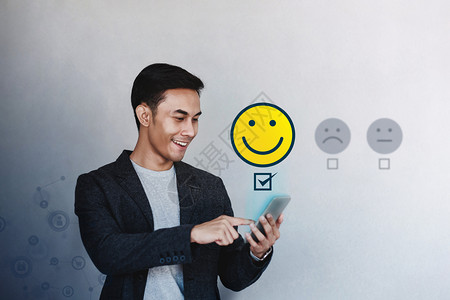 技术照片质量客户经验概念青年商人在满意线调查中给予积极评价乐客户通过智能手机为卓越服务提出微笑脸孔一用户经验图片