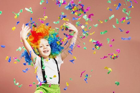 移动男孩在小丑假发上跳玩得开心庆祝生日一个孩子的肖像扔了一个多色的锡轮和彩蛋生日男孩积极情绪浮夸的喜悦图片