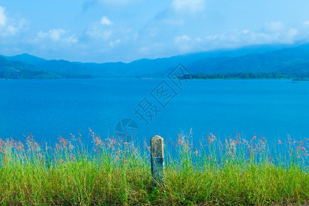 天气蓝色的田园诗般湖和山后面路边的草地在湖和山后面图片