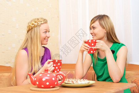 水平的两位年轻女士坐在桌边喝茶裙子休息图片