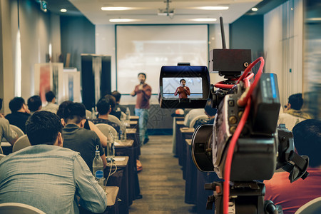 男人在商业或教育研讨会活动和概念的议室放映屏幕上在展示式屏幕上播放亚洲演讲人随身穿便装在舞台上拍摄的闭场录像片段制套装人们图片