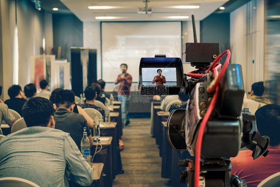 男人在商业或教育研讨会活动和概念的议室放映屏幕上在展示式屏幕上播放亚洲演讲人随身穿便装在舞台上拍摄的闭场录像片段制套装人们图片