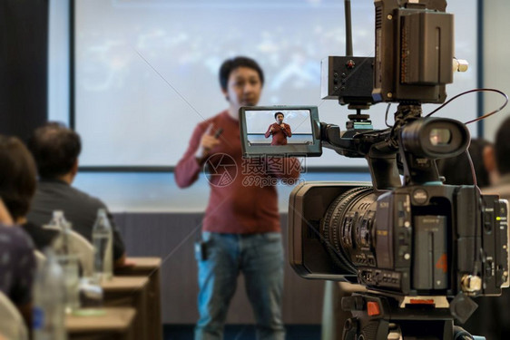 在商业或教育研讨会活动和概念的议室放映屏幕上在展示式屏幕上播放亚洲演讲人随身穿便装在舞台上拍摄的闭场录像片段制解释扬声器企业家图片