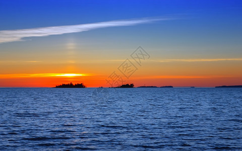 日出复制在俄罗斯卡雷利阿白夜晚的奥涅加湖日落地平线上的海面太阳和远岛屿的休眠带下方金色亮光俄罗斯卡列利亚遥远图片