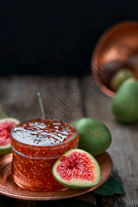 收成黑暗的东在土耳其铜盘上的玻璃罐子里装有Fig果酱旁边有半个新鲜的无花果背景特写时有水果准备秋季的甜点黑木背景复制空间图片