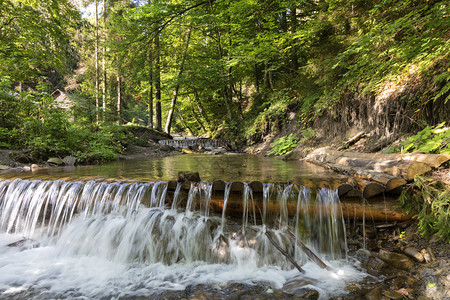 灌木丛在喀尔巴阡山脉一条溪的连层瀑布中蓝天反映了喀尔巴阡山脉一条流不断攀升的瀑布在喀尔巴阡山脉一条河的接层瀑布中森林流动图片