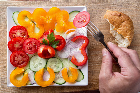 从上面看健康天然食物的概念用新鲜切开的蔬菜把叉子压在盘上用新鲜切开的蔬菜来砍掉板子上的叉和对盘切碎的一种黄色图片