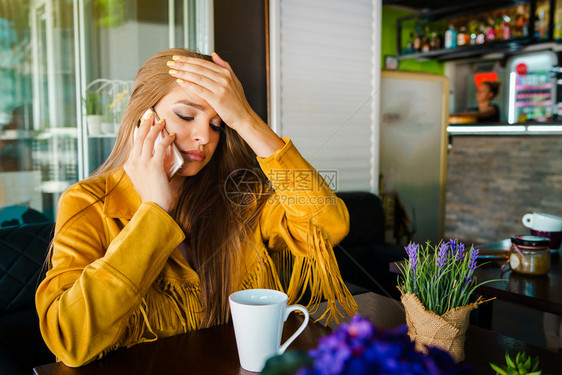 戏剧女恼人的在咖啡馆餐厅与移动电话通的年轻美女肖像收到令人不安的惊消息她头顶着手前额有令人吃惊的意外消息图片