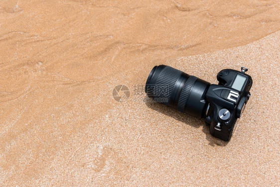 数字的镜片在极端环境中旅行和试验时摄影师DSL用DSR摄像机在水海浪的滩上打湿时使用带长光镜头的DSLR照相机进行防水测试下图片