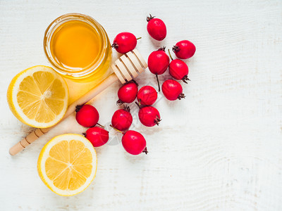 白木板上的新鲜黄柠檬一壶蜂蜜和红浆果风景近视孤立的防冷新黄色柠檬一壶蜂蜜和红莓子概念罐家图片