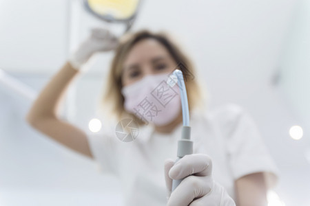 戴外科口罩的女牙医手持钻孔工具图片