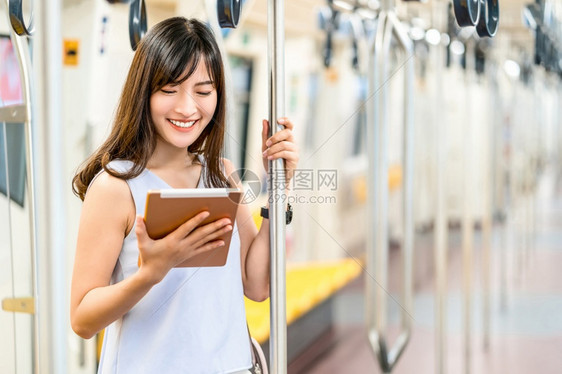 亚洲青年女乘客在大城市japanesechinese朝韩生活方式和日常通勤和运输概念上旅行时利用地铁火车技术平板进行社会网络使用图片