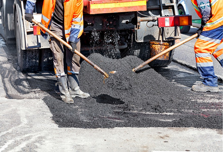 道路指示标乌克兰人行道铲子配有铁的公路工人作组以新沥青更部分道路在建设文本地点复制空间A路工小组用新鲜沥青修筑部分道路时更新该并其中的沥青背景