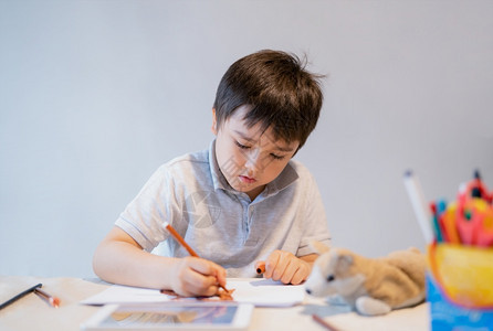 在桌上画画的小男孩图片