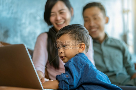 有儿子的亚洲家庭正在透过技术笔记本电脑寻找漫画当生活在自学或家庭校的阁楼里时一起玩游戏家庭学校的概念FamilyhomeScho图片