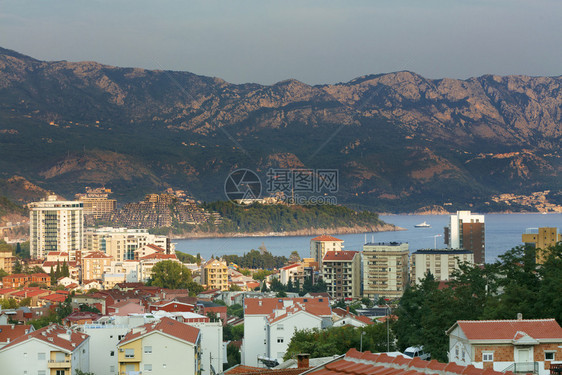 太阳现代城市布德瓦Budva在海湾和山链背景下的象在海湾和山链背景下的现代城市布德瓦里维埃拉BudvaRiviera在日落光照耀图片