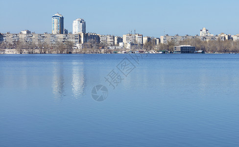 蓝色的平静河面在市区映衬下着春天空的蓝色春空的深蓝映衬着平静的河流自然美丽图片