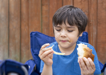 孩子在花园里吃汉堡和混合蔬菜饥饿的男孩坐在外边吃自制野餐春或夏季户外活动Spring或Summer愉快保持或者图片